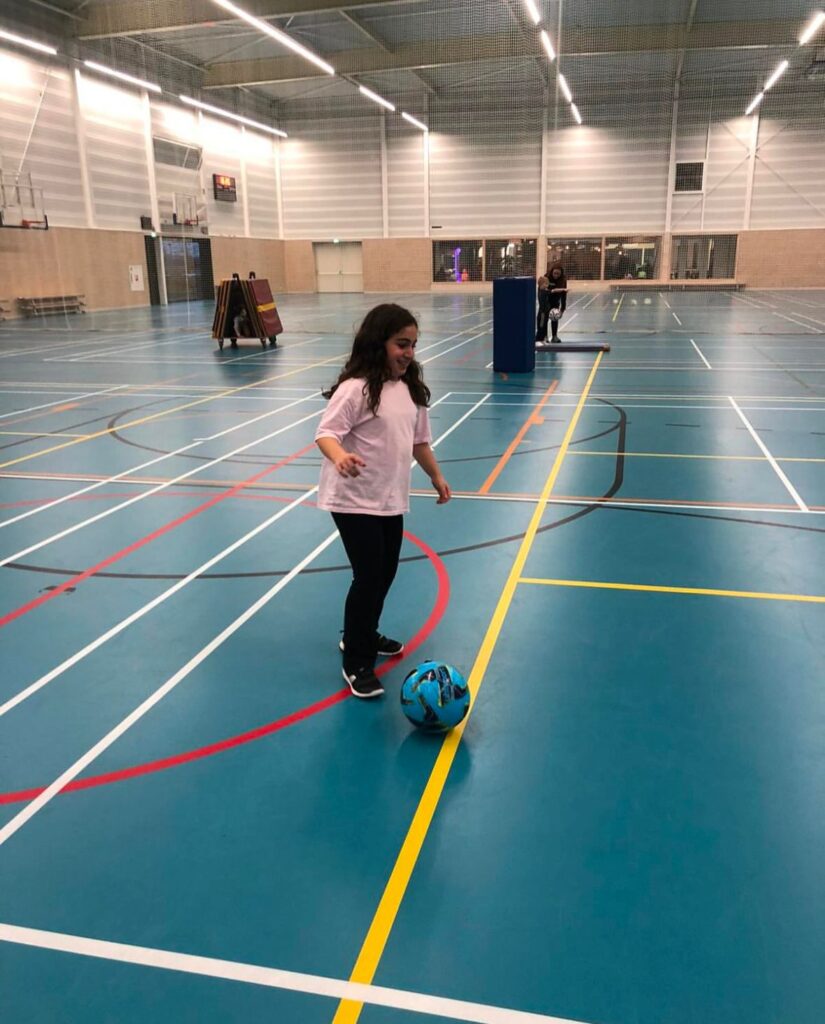 Kind voetbalt in de gymzaal bij Sport-BSO Flekss