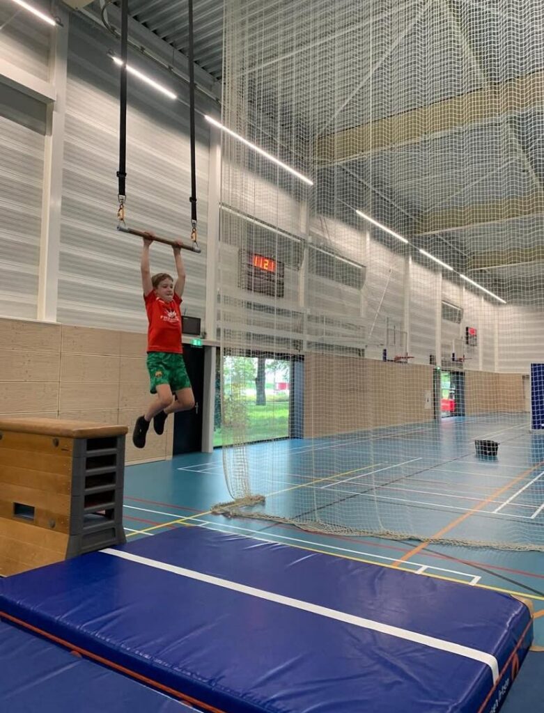 Kinderen zwaaien aan trapeze stok bij Sport-BSO Flekss
