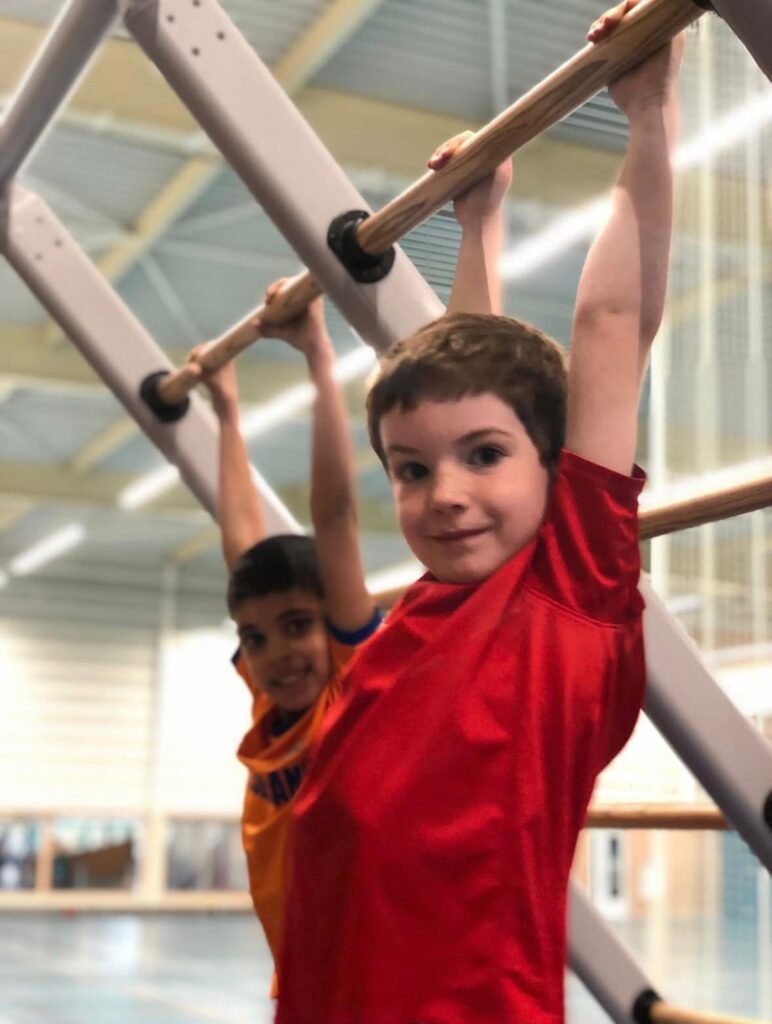Kinderen hangen aan het wandrek bij Sport-BSO Flekss