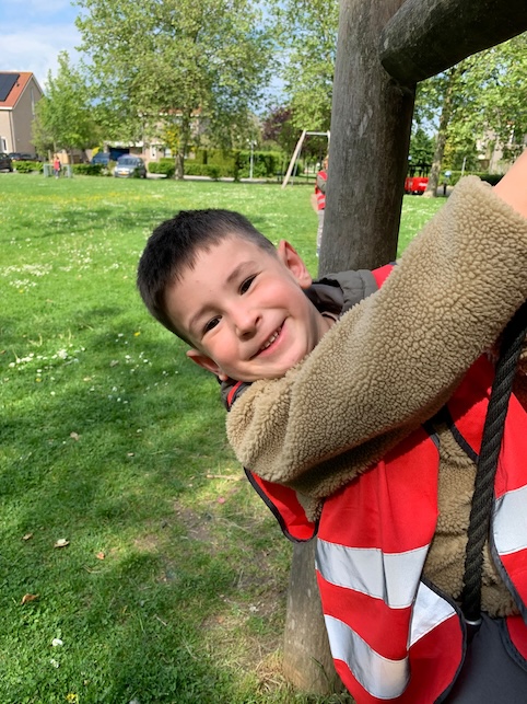 kind hangt aan klimrek bij het buitenspelen
