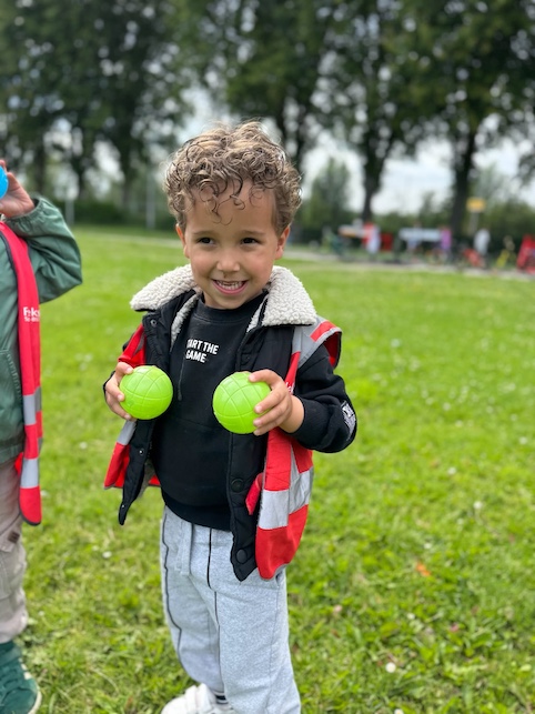 kindje heeft een jeu de boules ballen vast