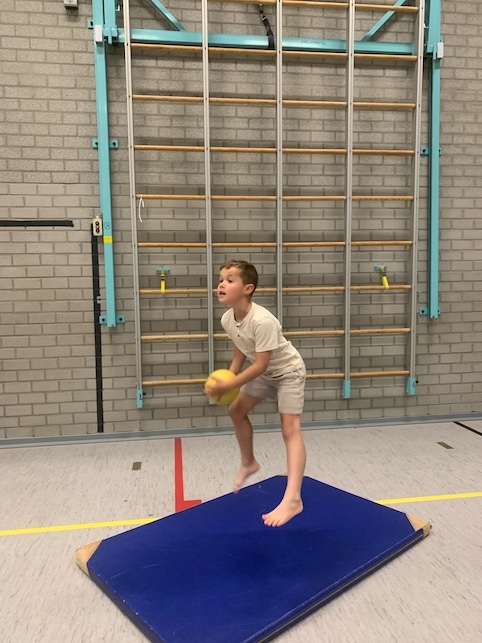 kindje speelt met een bal in de gymzaal