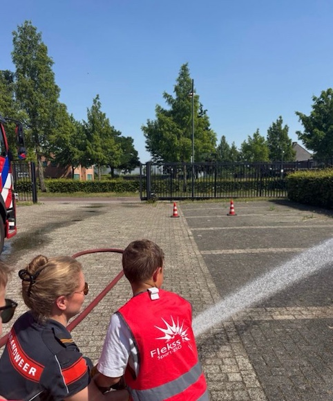 kindje spuit met water bij de brandweer