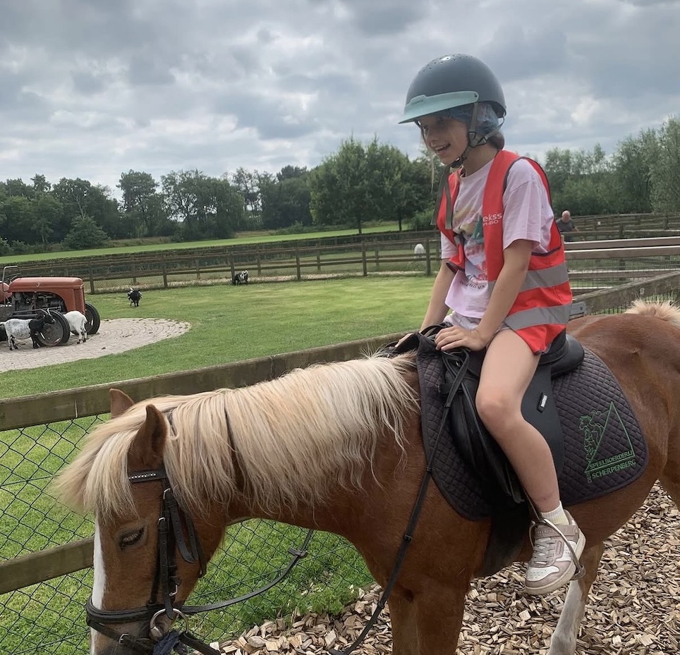 kindje zit op een paard