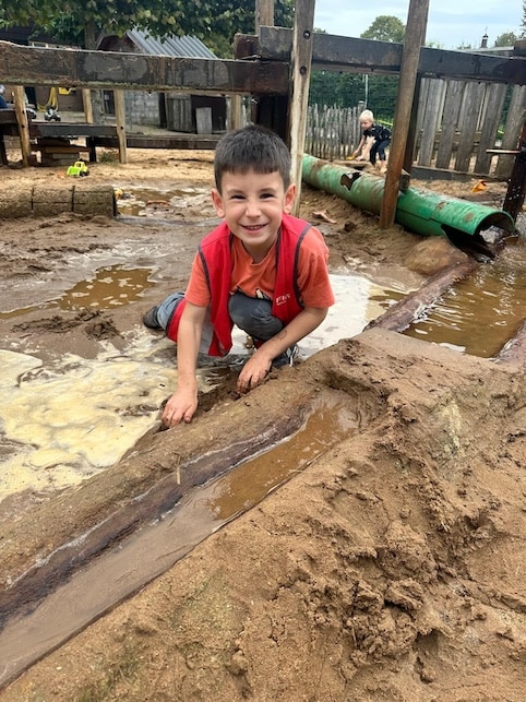 kind speelt met zand in de zandbak